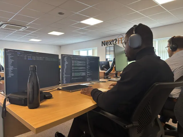 A software engineer working across dual monitors on an AI project.