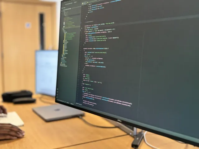 A developer's desk with two monitors showing code for a custom application.