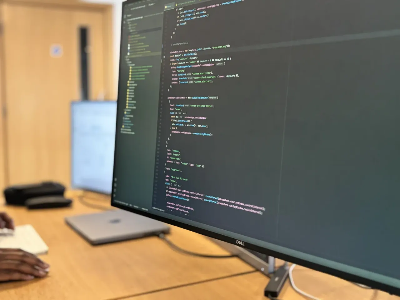 A developer's desk with two monitors showing code for a custom application.