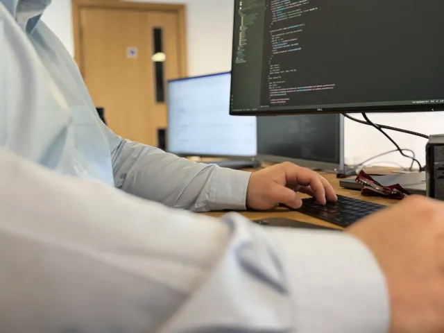 Close-up of hands writing code on a laptop keyboard.